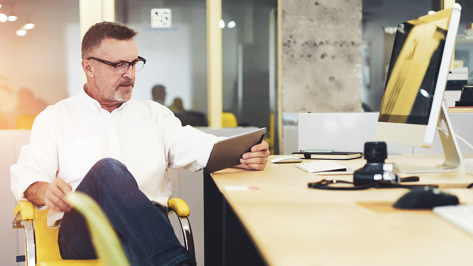 A business owner in an office looking at financial data on a tablet device