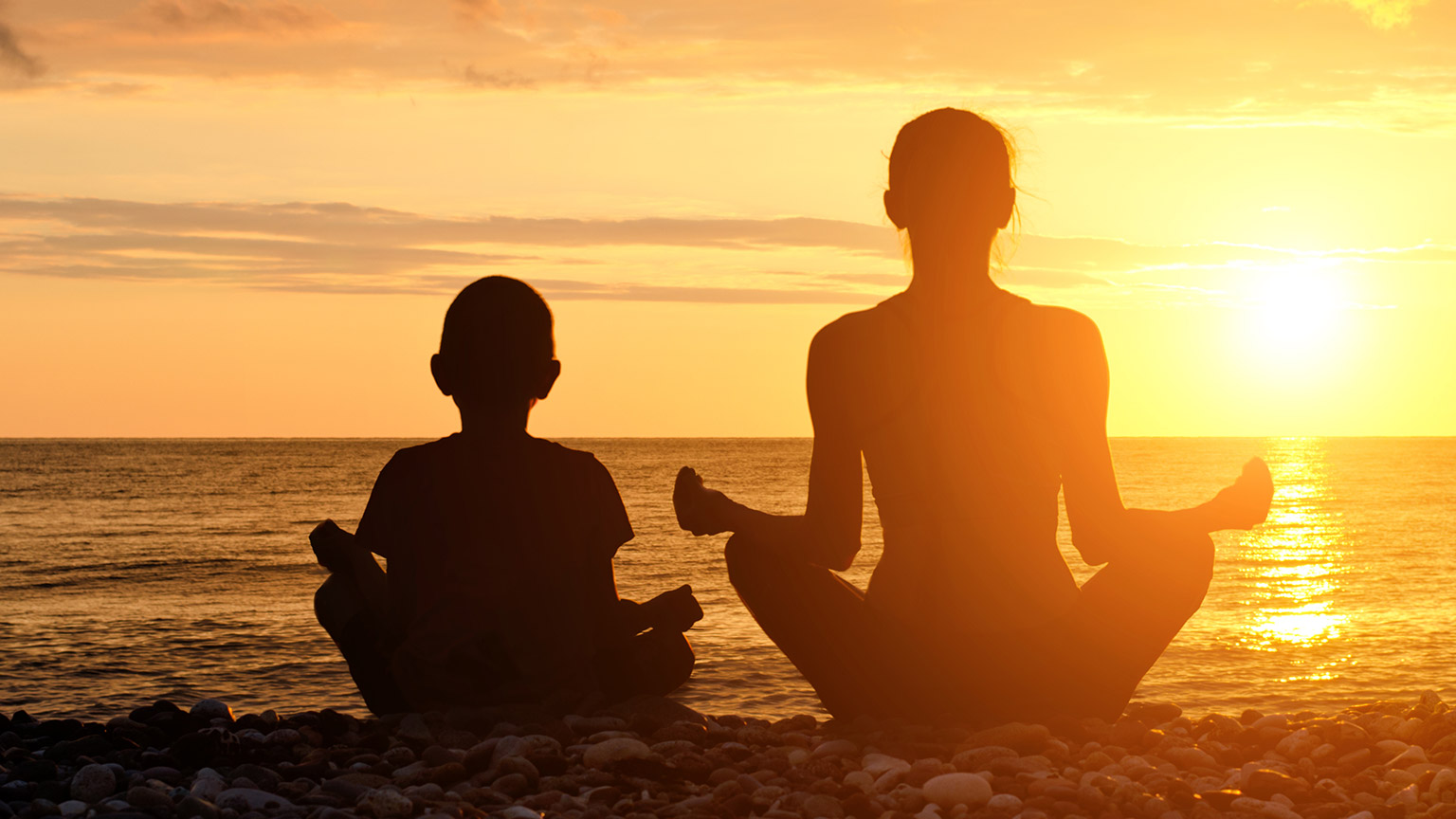 People sitting on a beach staring at the sun