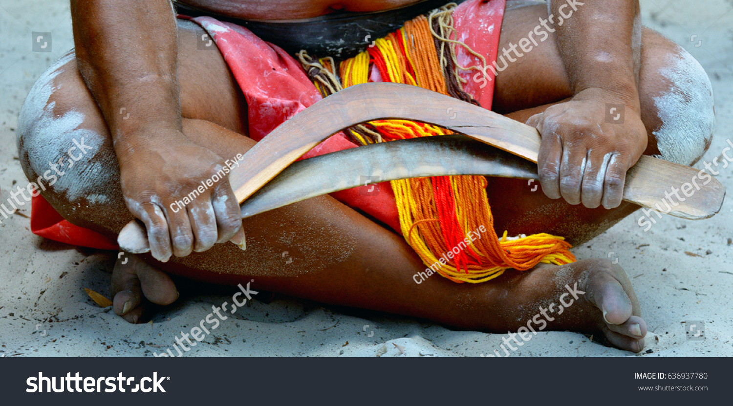 Australian Aboriginal man sitting on the ground holding boomerangs in the tropical far north of Queensland, Australia