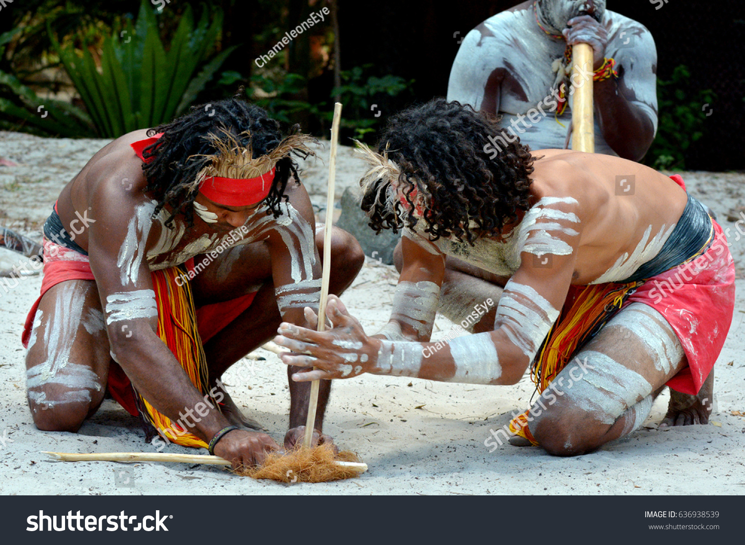 Group of Australian Aboriginals men demonstrating fire making craft during Aboriginal culture show in the far tropical north of Queensland, Australia.