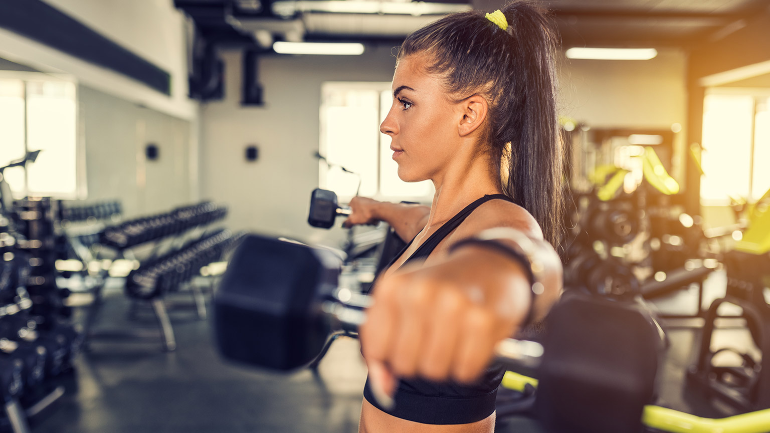 A person in a gym doing exercise with dumbbells