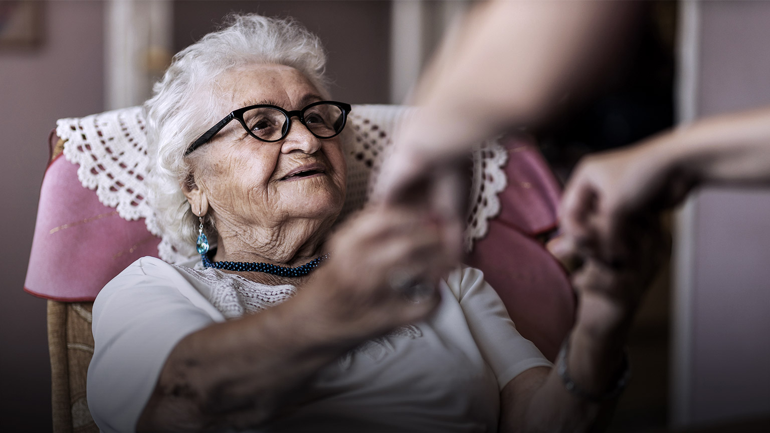 Elder woman getting help to get up from an assistant