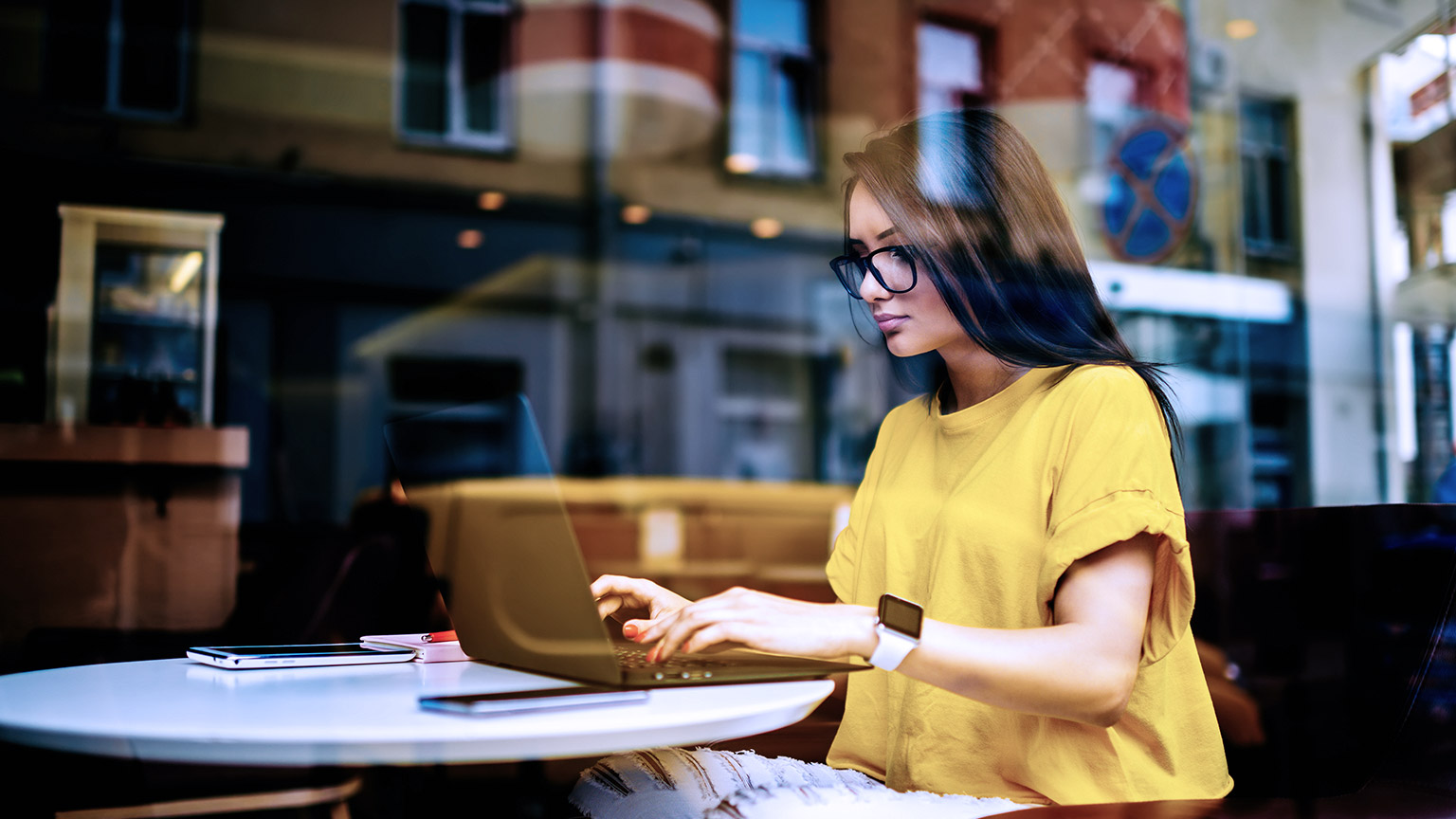 Woman working insdie a cafe with laptop