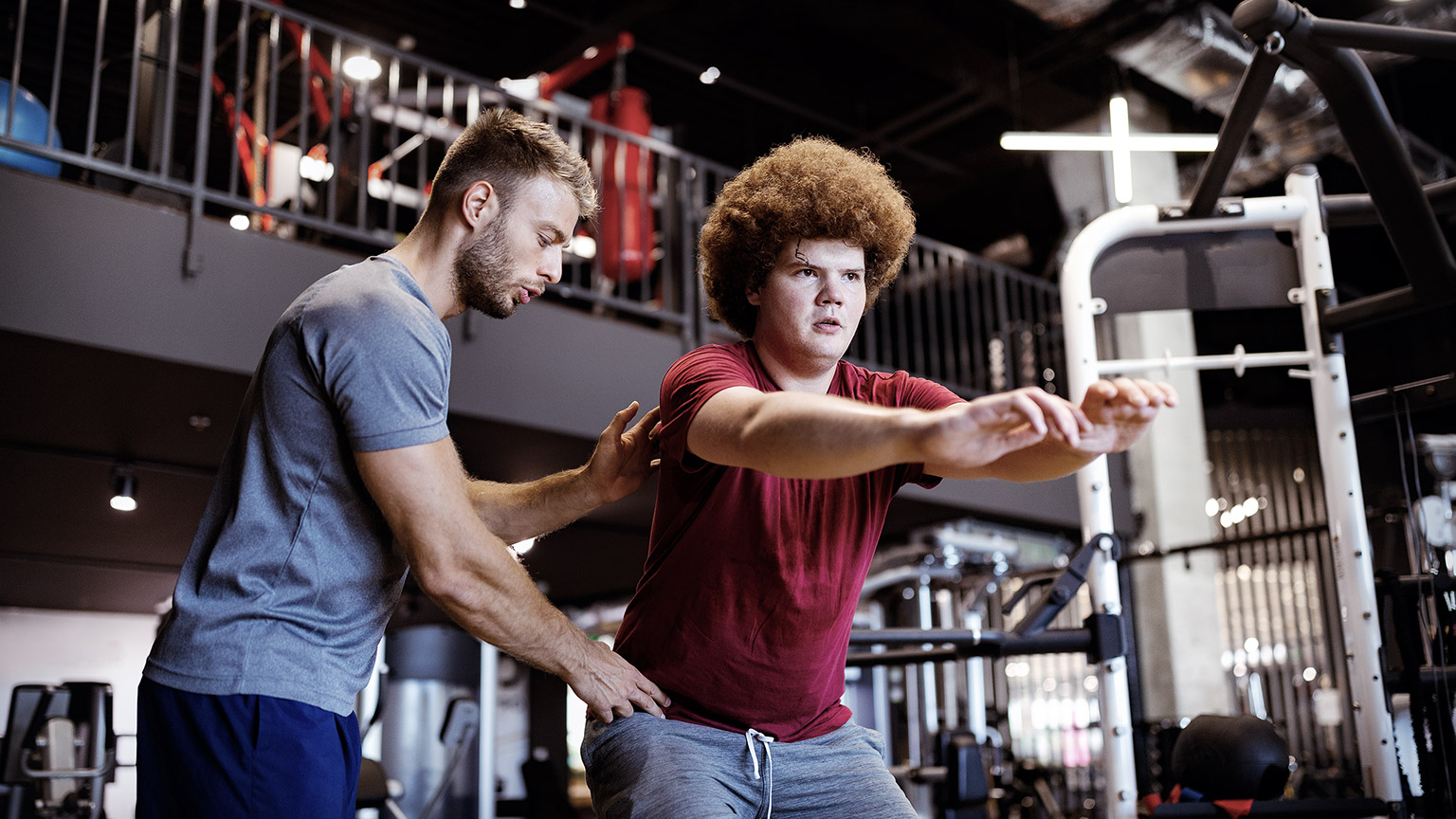 Overweight man guided by physical trainor