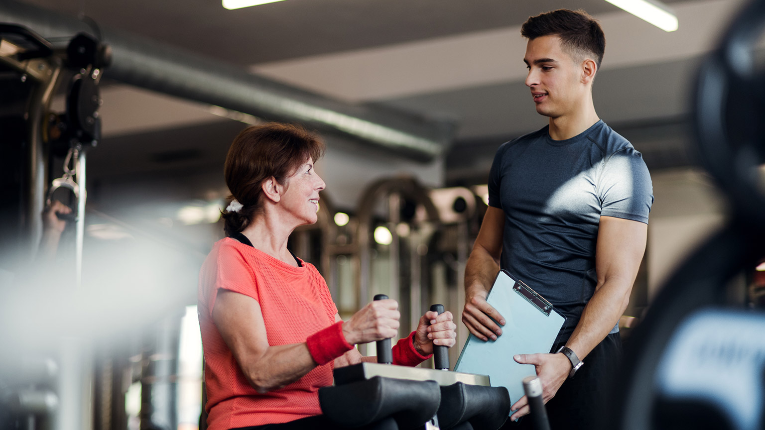 A young trainer talking to a client in a gym