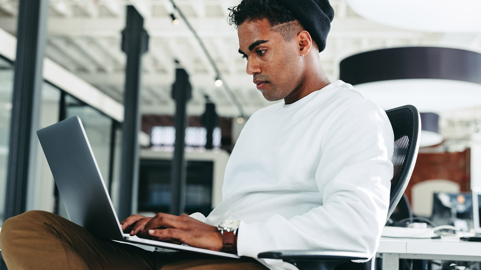 A programmer working on a laptop in a modern office environment