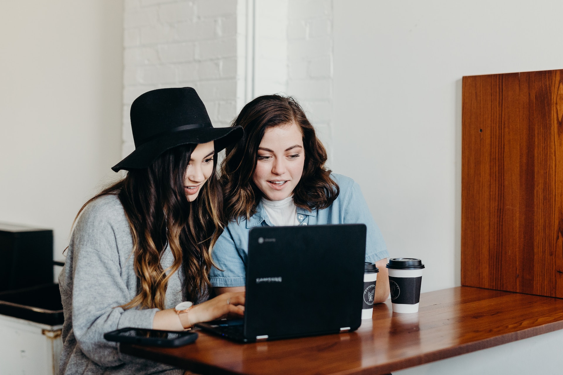 Two women discussing in front of a laptop.