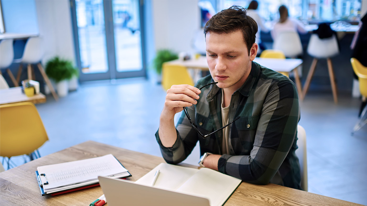 Man thinking with computer and paper notes