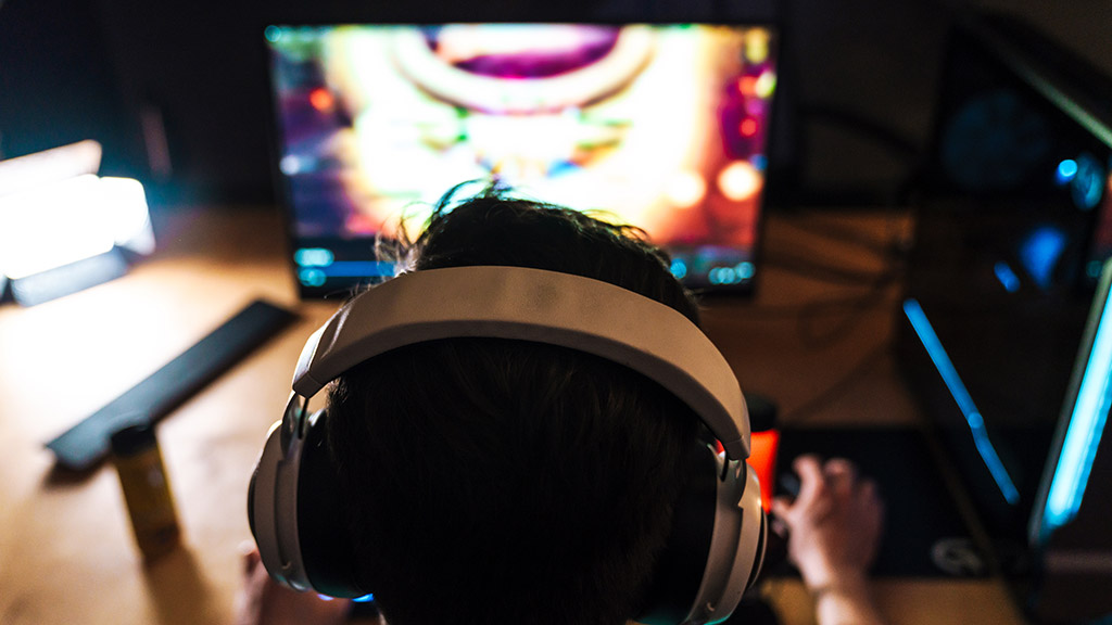 focused brunette man in headphones playing video game on computer