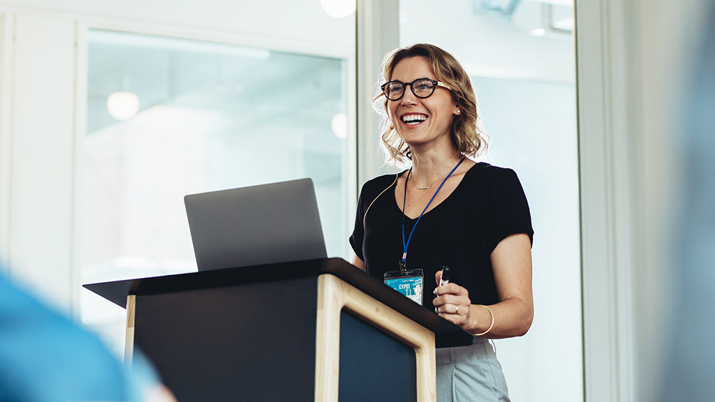 Businesswoman standing at podium with laptop giving a speech