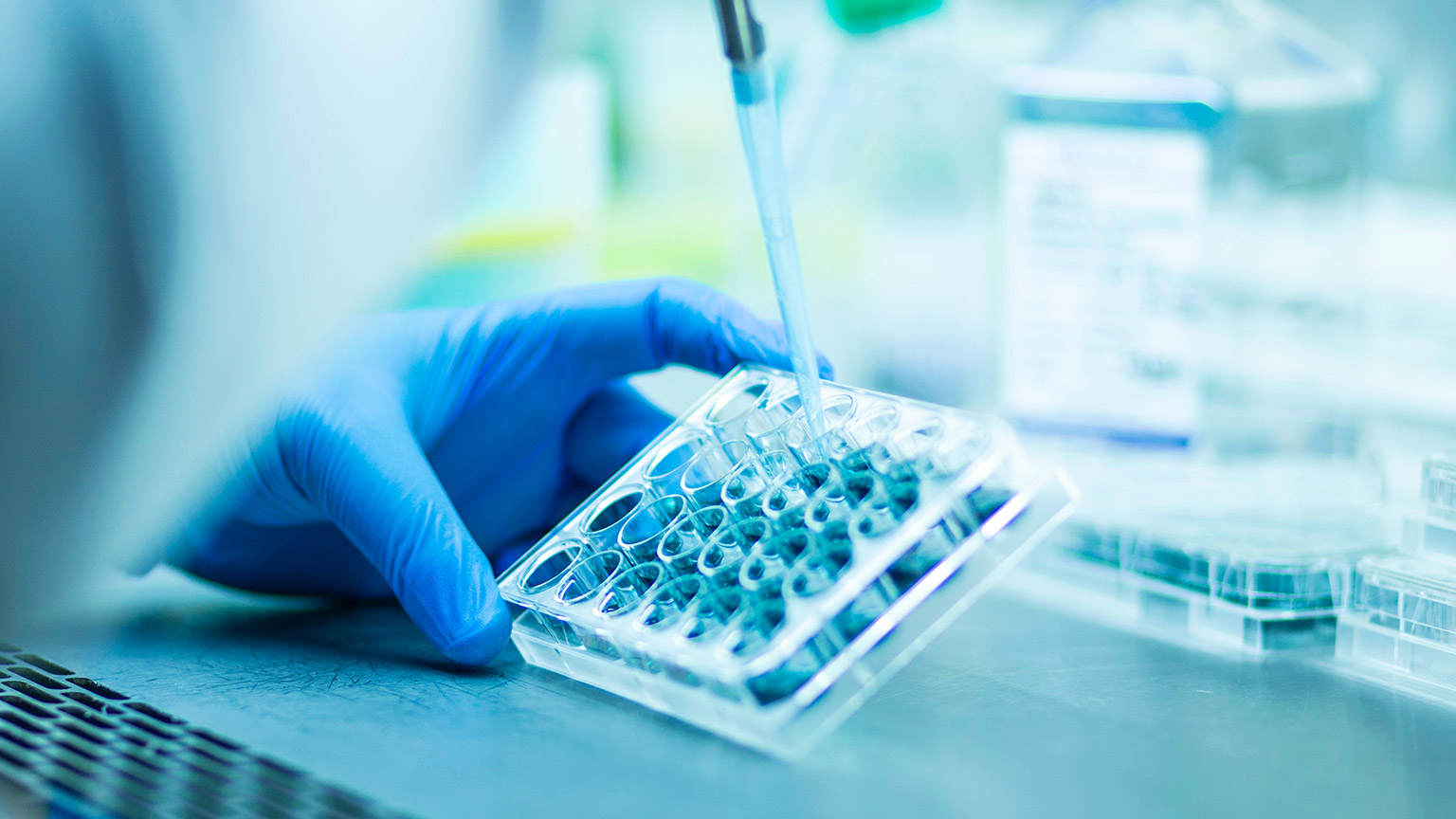 A hand in a rubber glove mixing pharmaceuticals