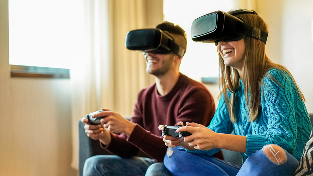 Young happy couple playing video games virtual reality glasses in their apartment