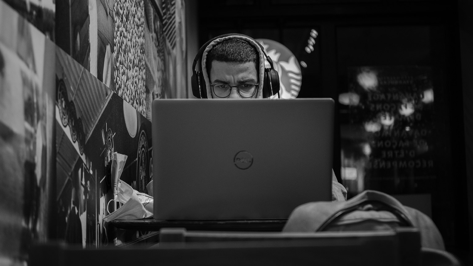 A hacker sitting in a cafe using a laptop