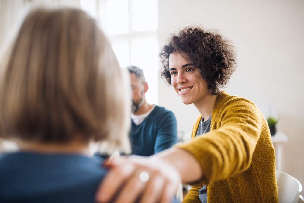 Men and women sitting in a circle during group therapy, supporting each other.