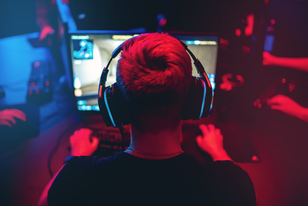 Professional gamer playing online games tournaments pc computer with headphones, Blurred red and blue background.