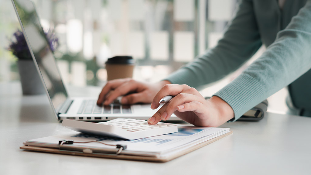 businessman working on desk office with using a calculator to calculate the numbers