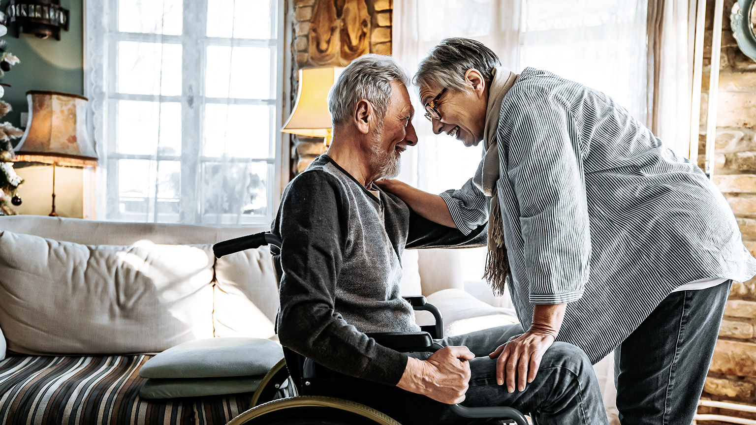 Matured man on wheelchair touching by old women, both happy