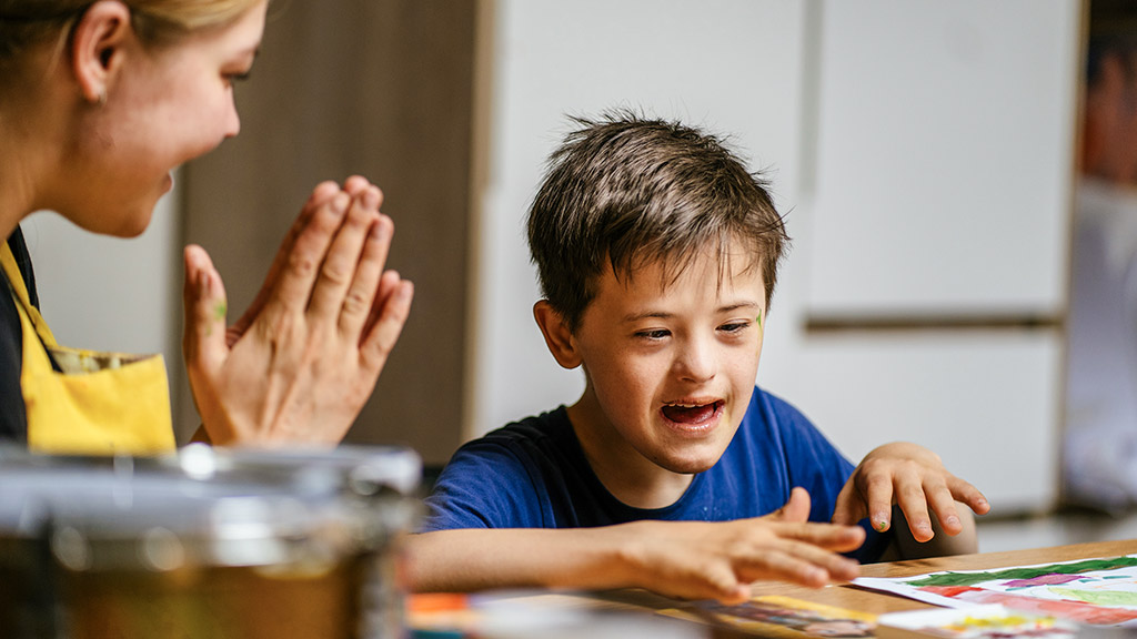 woman cheering up a boy with down syndrome