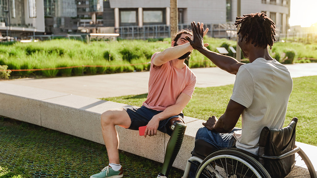 Multiracial people with physical disabilities greeting each other outdoor