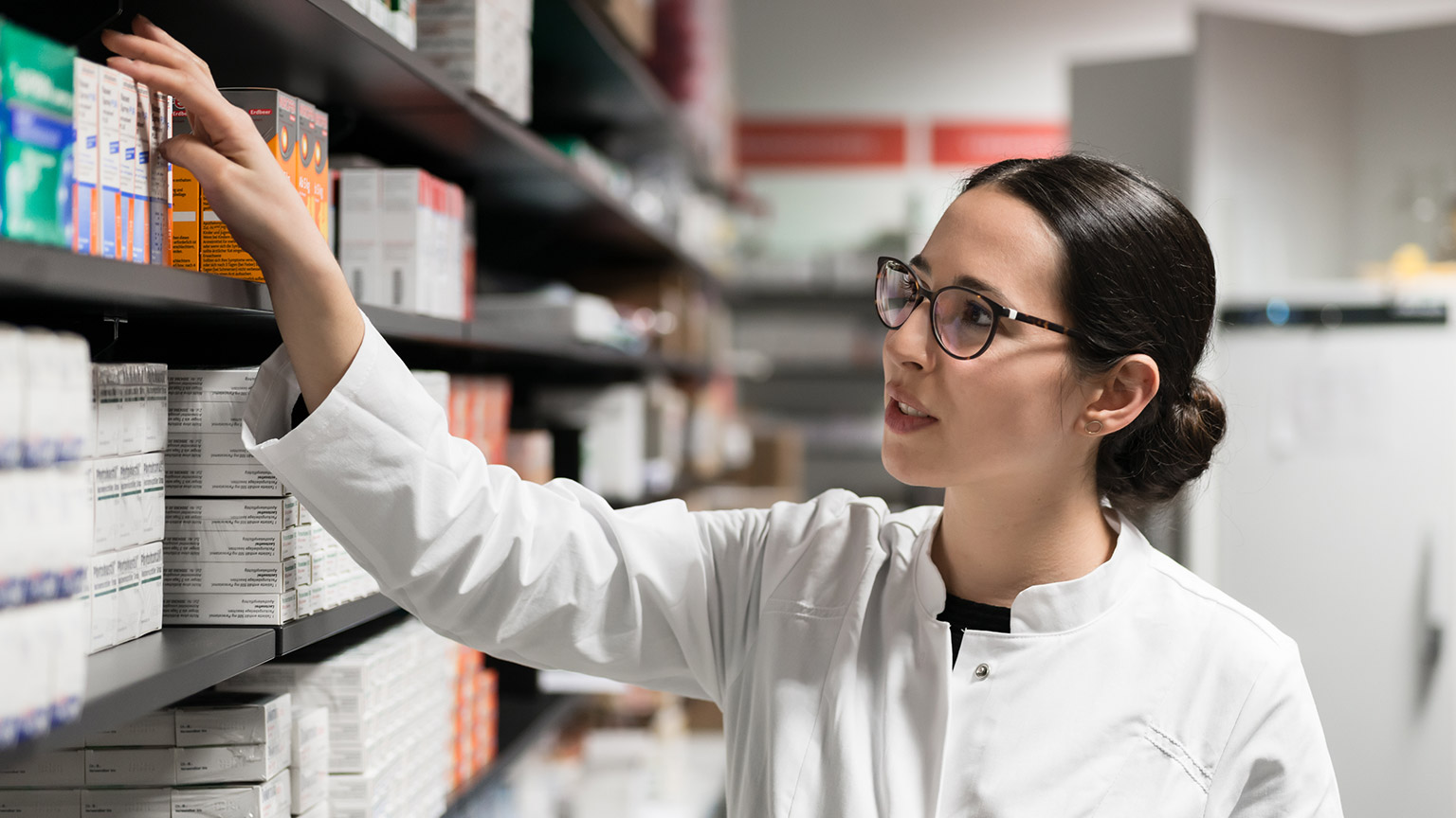 A pharmacist taking medication off the shelf