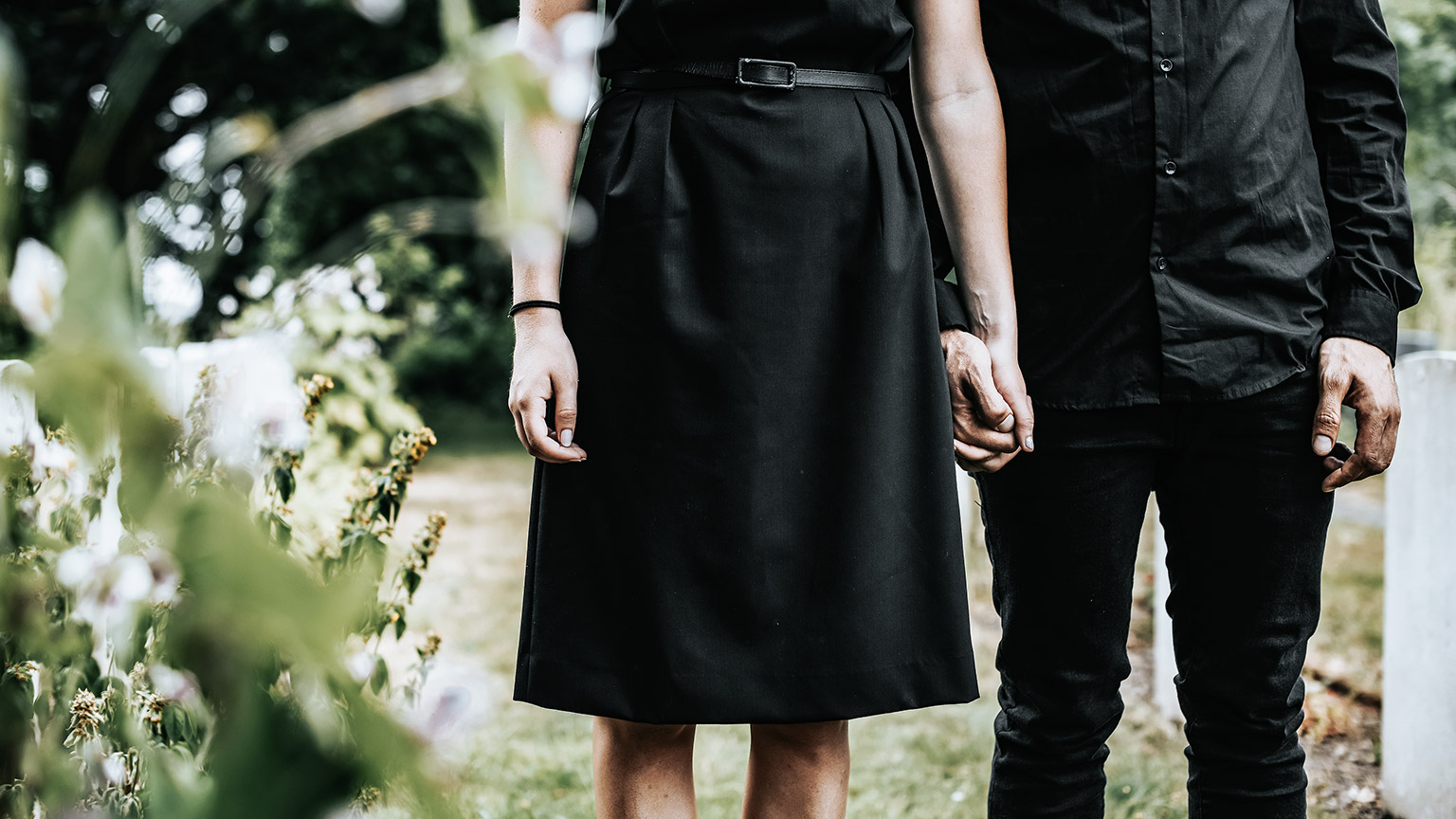 couple holding hands at graveyard