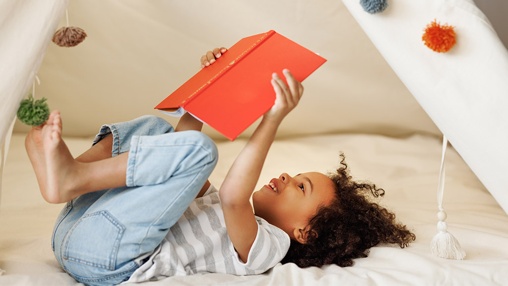 Portrait of cute little african american kid curly boy with book smiling