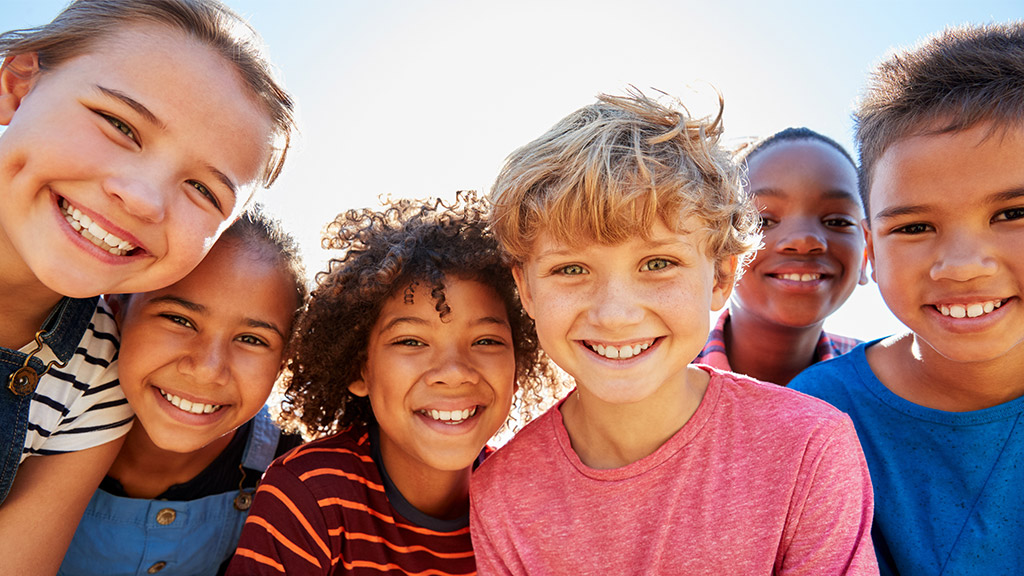 Close up of pre-teen friends in a park smiling to camera