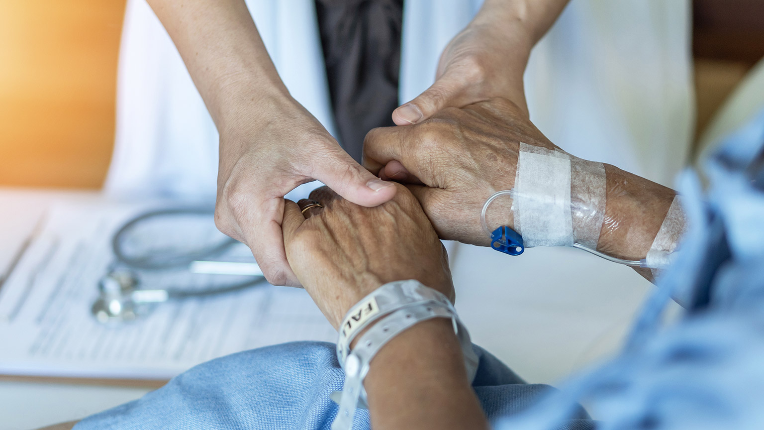 A close view of a person holding the hands of a patient