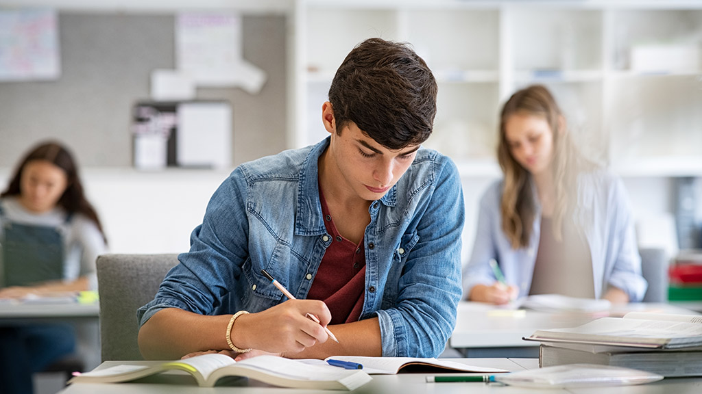 Focused young man taking notes from books for his study