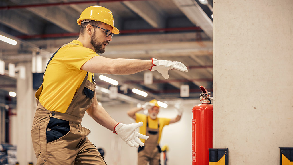 Young man using fire extinguisher in warehouse.Fire extinguishers.