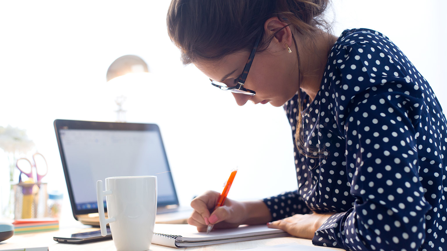 A person writing notes at a desk