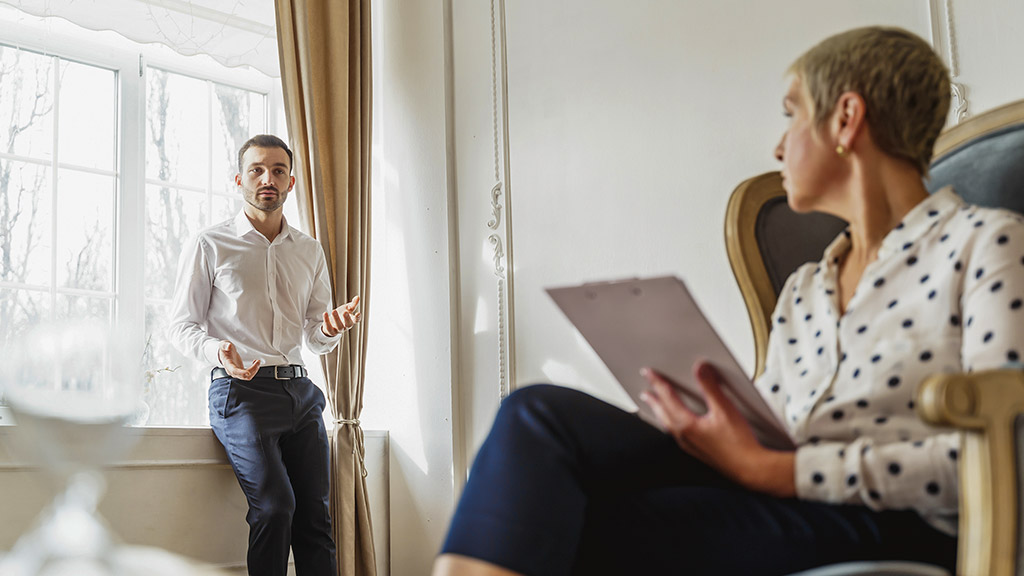 young male patient talking to his female psychoanalyst in her office