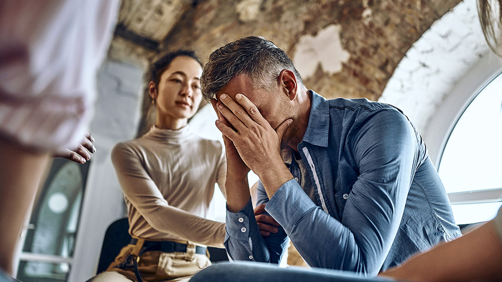 therapy session participants supporting crying desperate guy