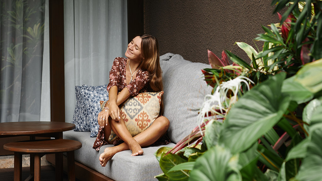 Young beautiful woman enjoys relaxing on the terrace of a resort hotel in Bali.