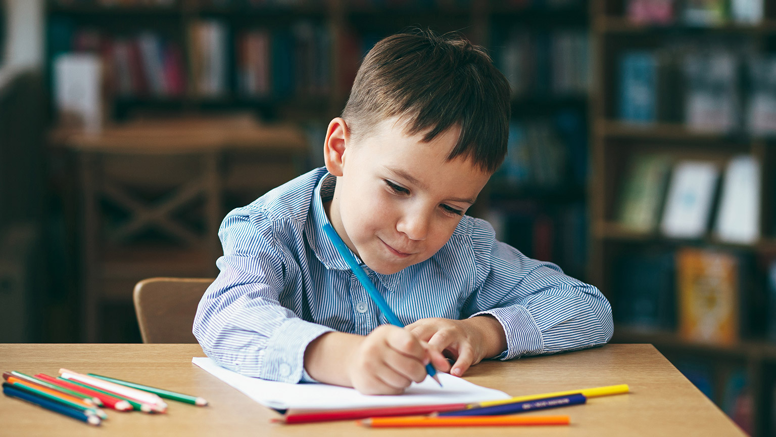 A child writing on paper with pencils