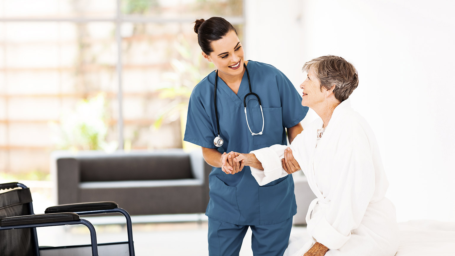 young female caregiver helping senior woman getting up