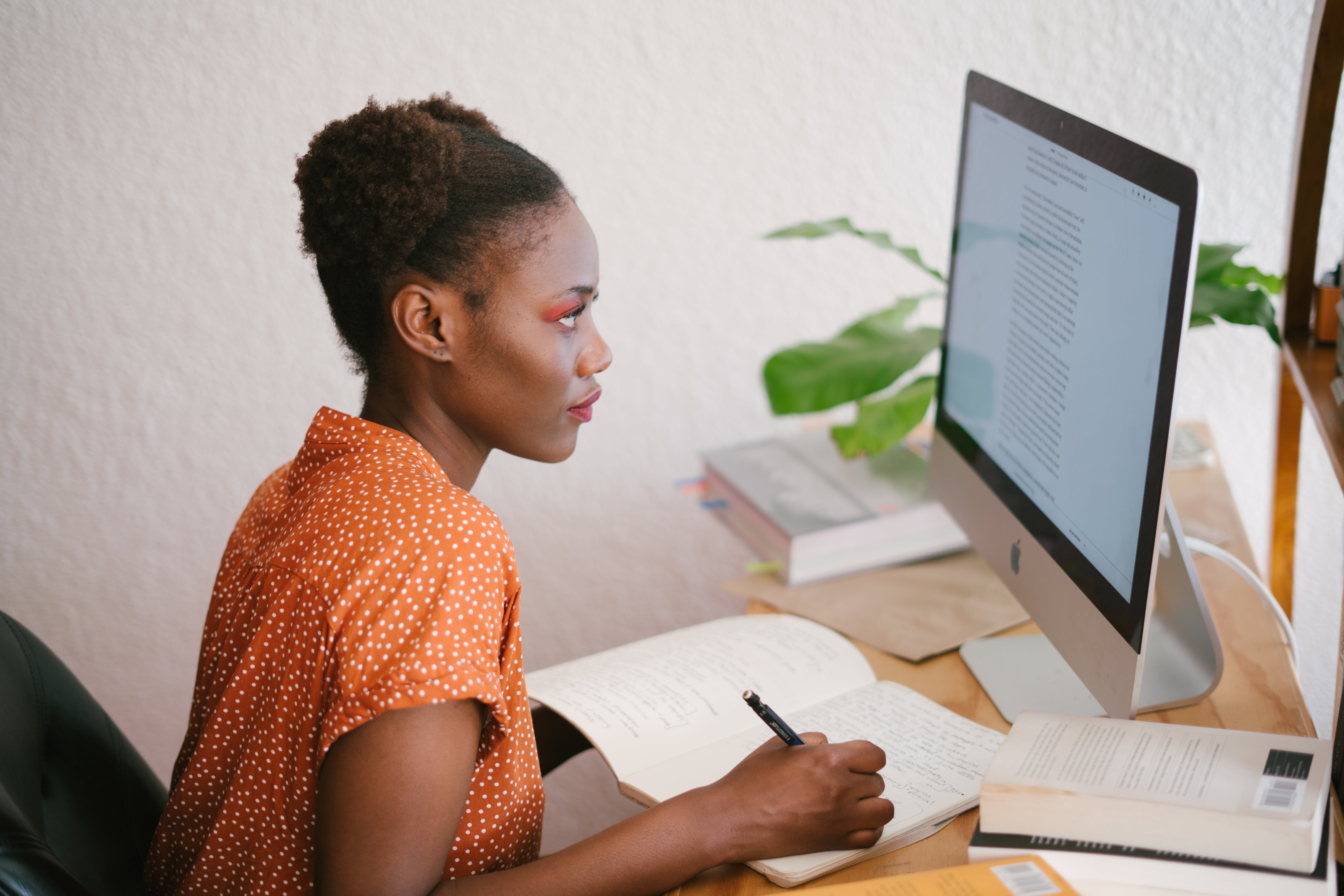 Woman sits at her computer, writing notes