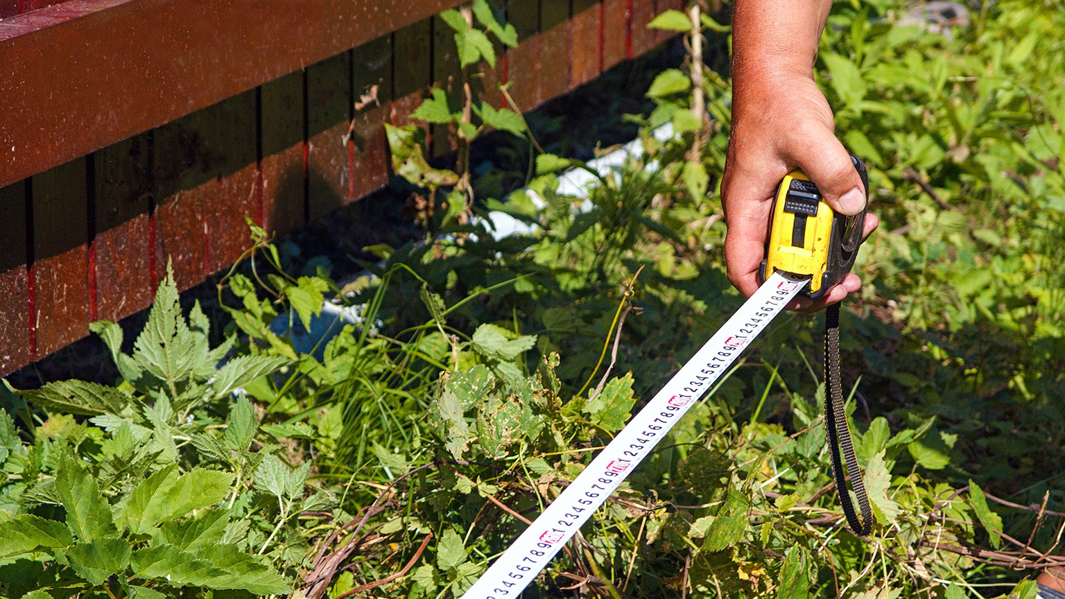 A person measuring for a new garden bed