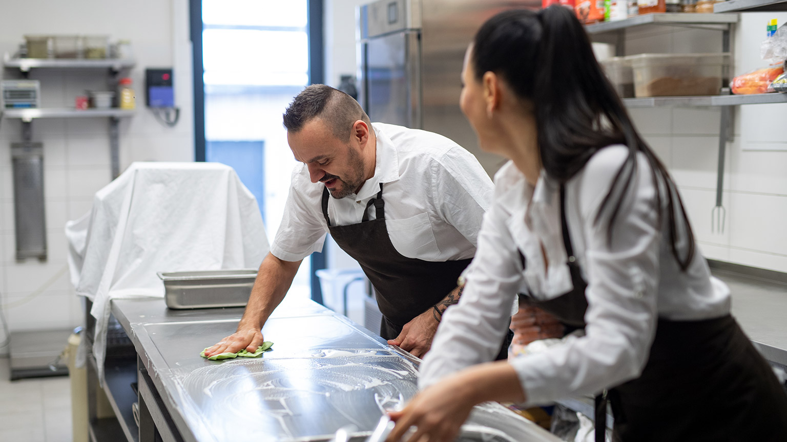 Two people cleaning a professional kitchen