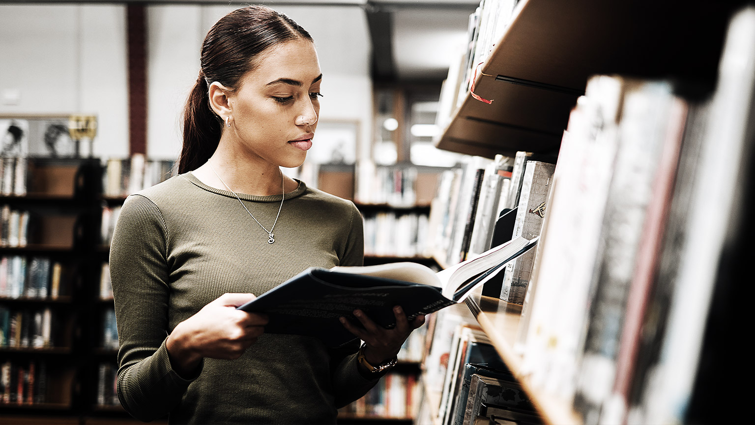 Student studying using computer and textbooks