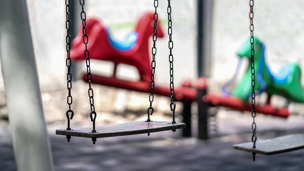 Empty swing at a playground. Sad dramatic mood for negative themes such as bullying at school, child abuse, pedophilia, traumatic childhood or kidnap.