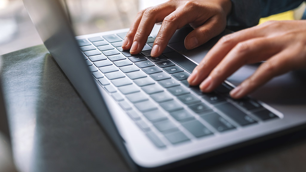 Closeup image of a woman working and typing on laptop computer keyboard