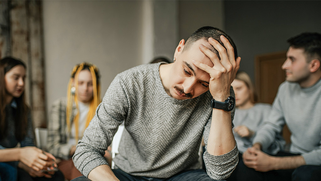 young caucasian man sit in the center during therapy session in support group for anonymous alcoholics, tired of drinking alcohol. healthcare concept