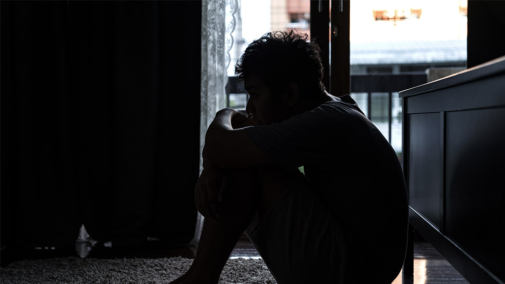 Depressed Asian man sitting on the floor