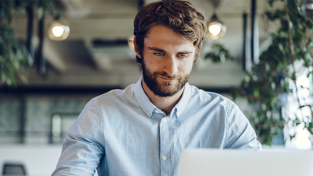 Businessman in shirt working on his laptop in an office. Open space office