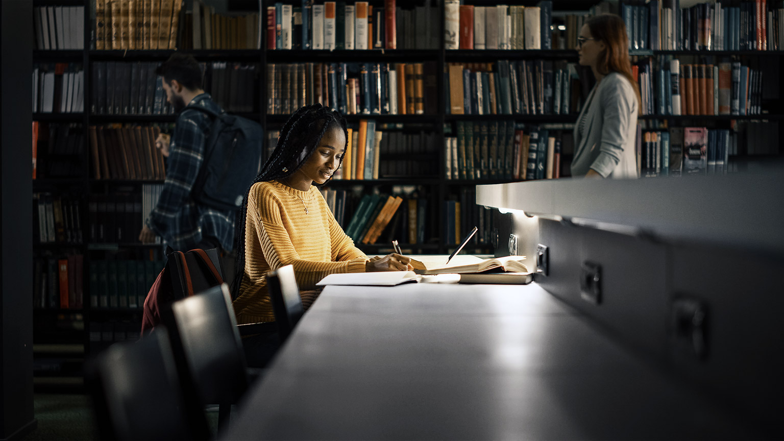 a person reading and taking notes in a library