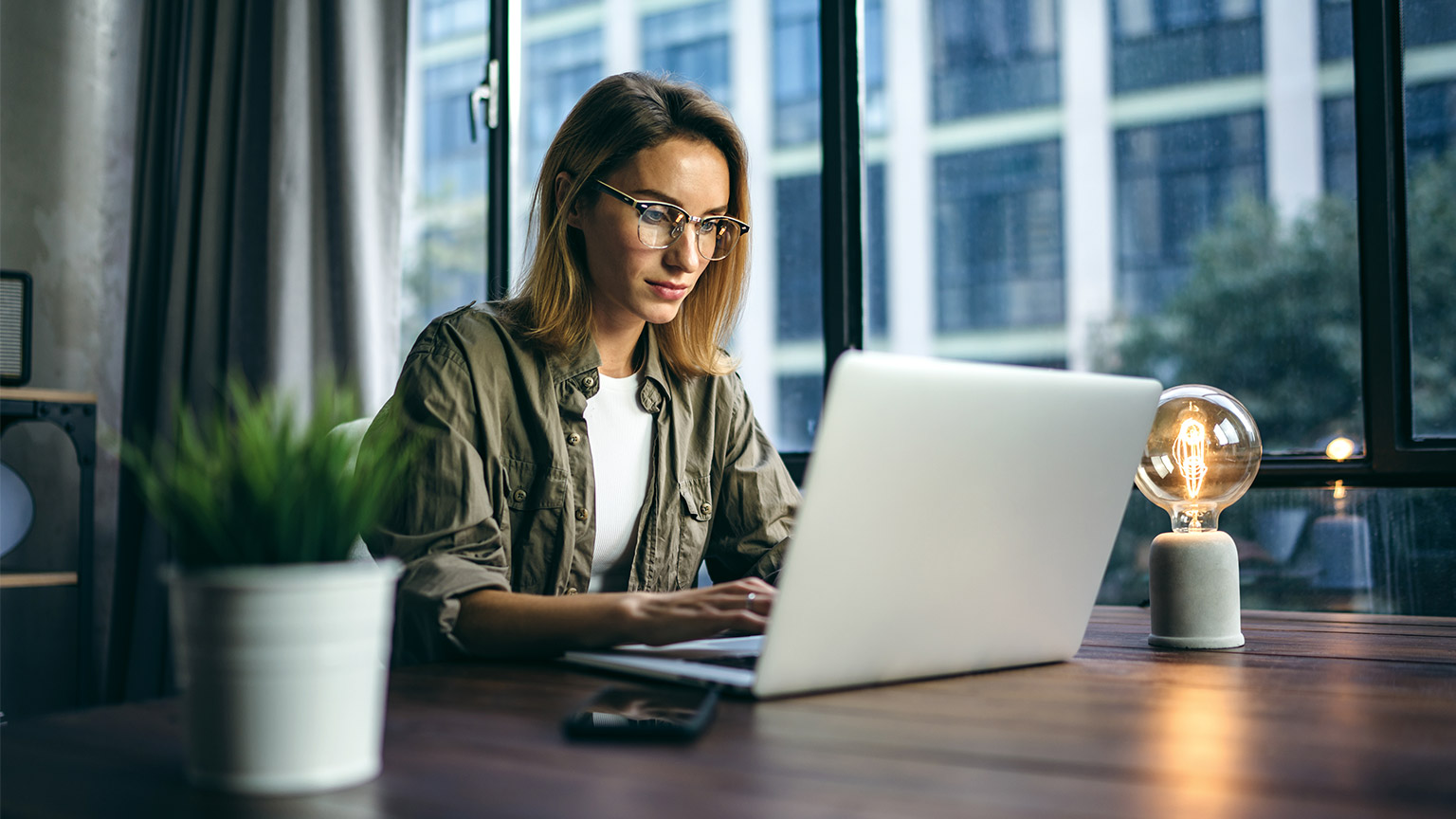 Young woman working with a laptop. Female freelancer connecting to internet via computer. Blogger or journalist writing new article.