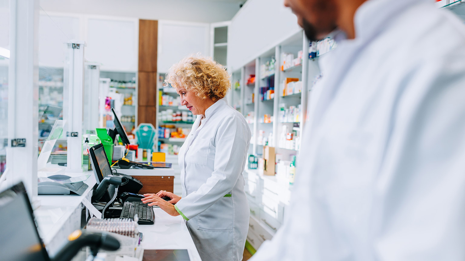 Two pharmacists working on computers