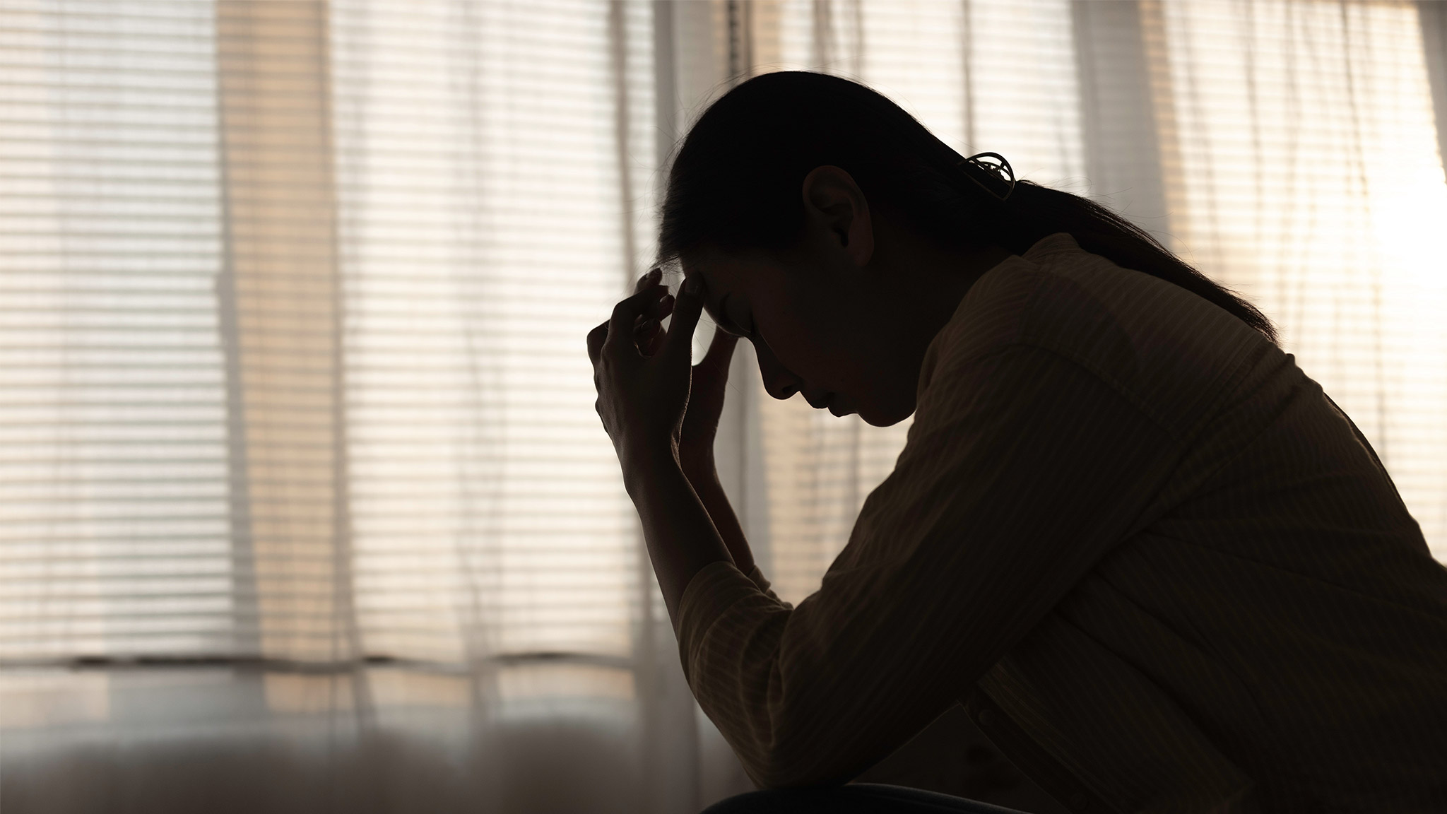 Female having depression sitting alone in bedroom dark corner.