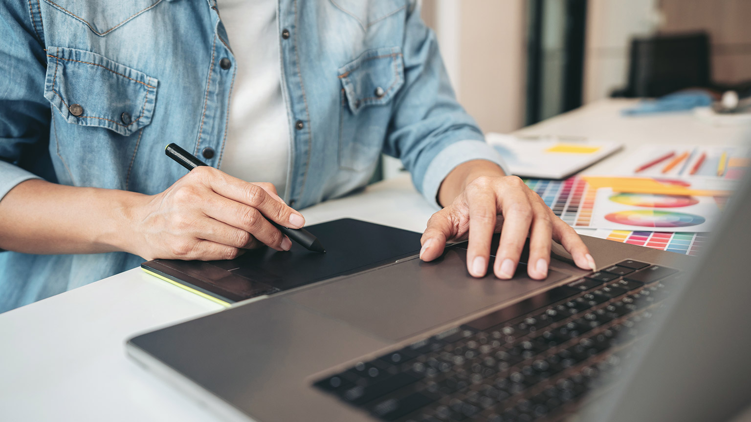 A designer working on a laptop and graphics tablet